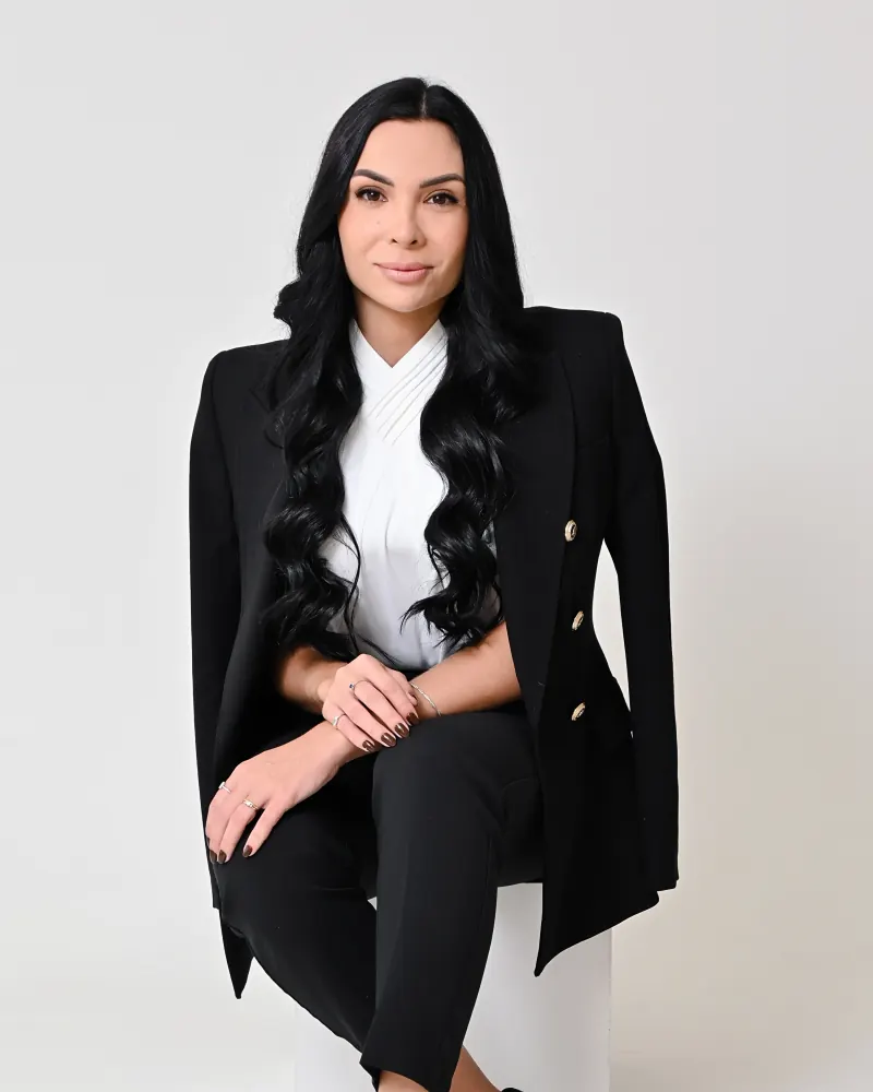 Dra. Giane Cieslak, advogada, sentada em estúdio, de blazer preto e blusa branca